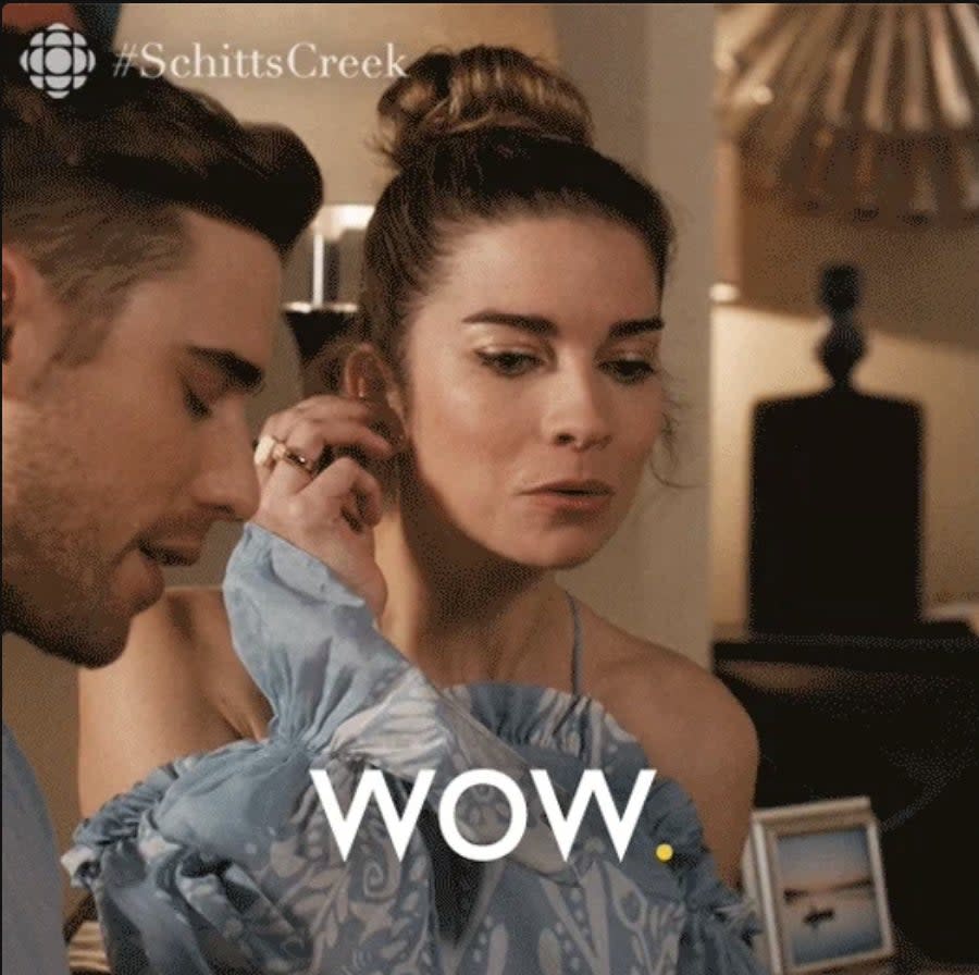 A woman in a fancy off-shoulder dress looks surprised, with