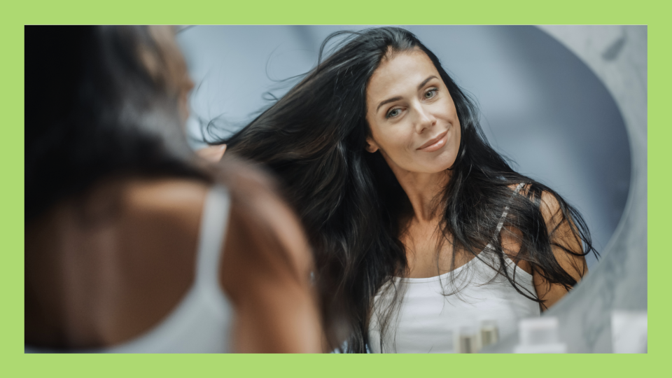 Woman running her hands through her hair in the mirror