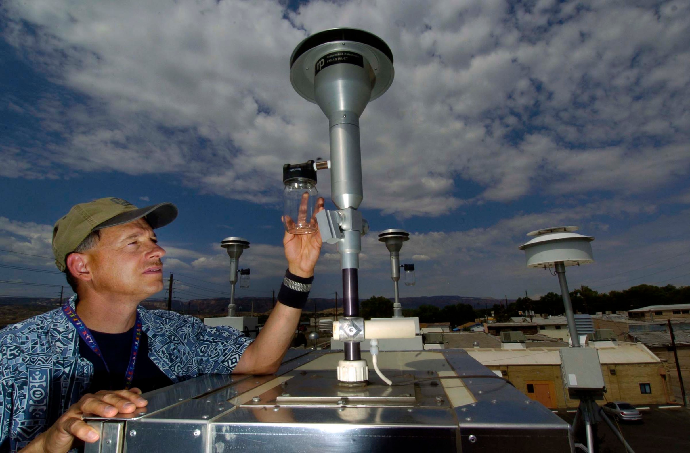 A person checking an air quality monitoring set-up outdoors.