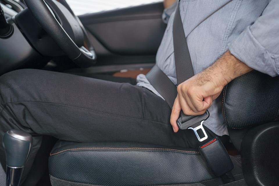 The person in a car connects their seat belt, highlights the safety and the responsible driving