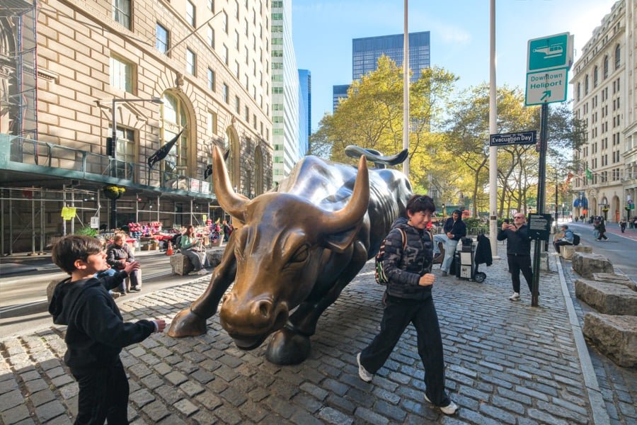 Tourists taking pictures with the charging bull statue near the stock exchange