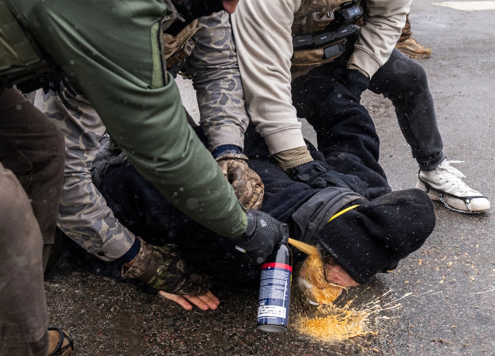 A person is pinned to the ground by federal agents and a chemical irritant sprayed directly into his face 