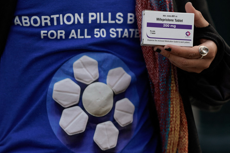 A pro-abortion rights activist holds a box of mifepristone/