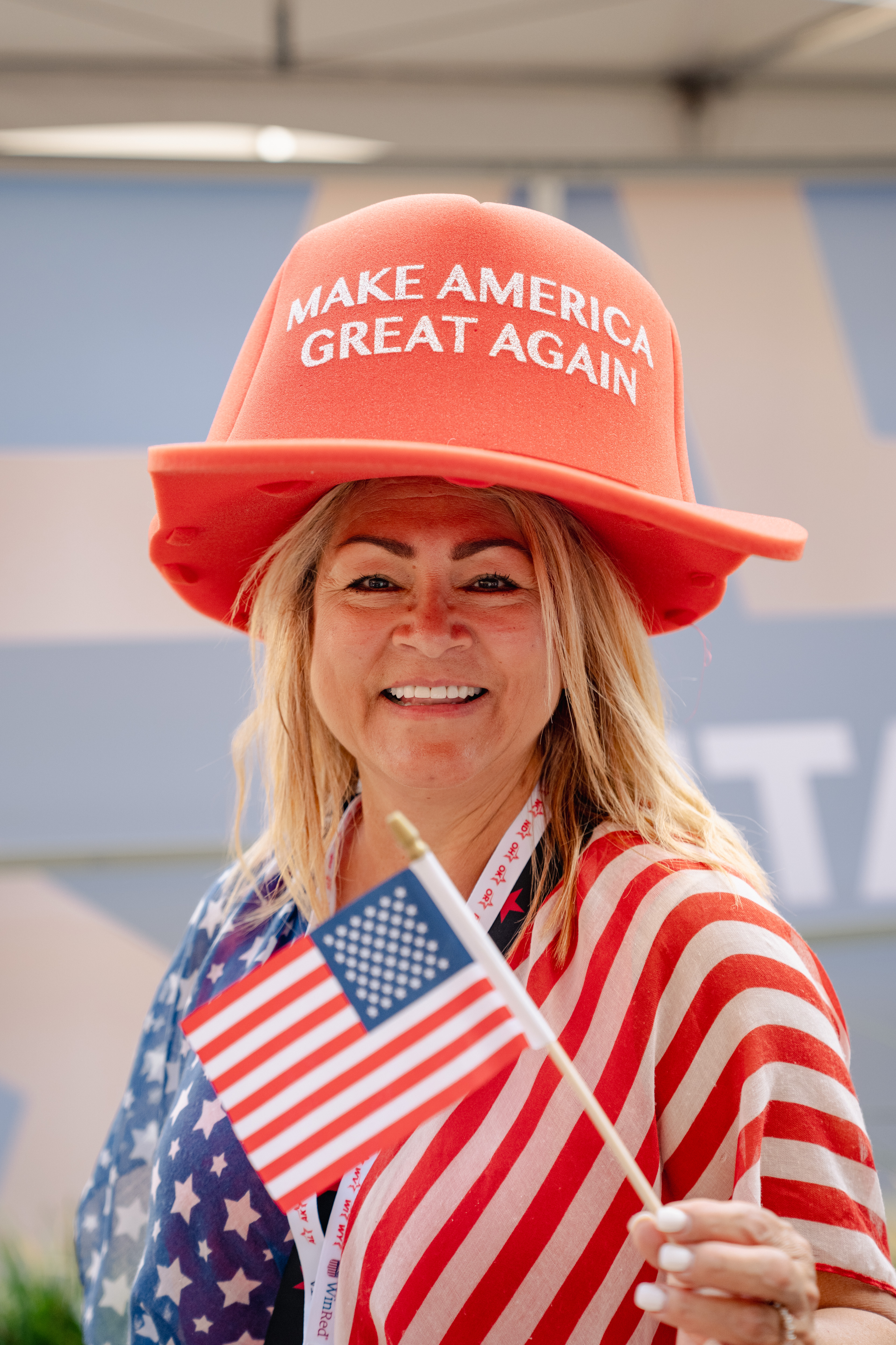 An attendee dressed in patriotic attire wears an oversized “Make America Great Again” hat.